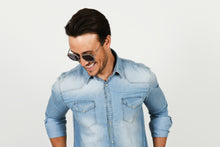 Load image into Gallery viewer, man wearing sunglasses and looking down and smiling wearing denim shirt
